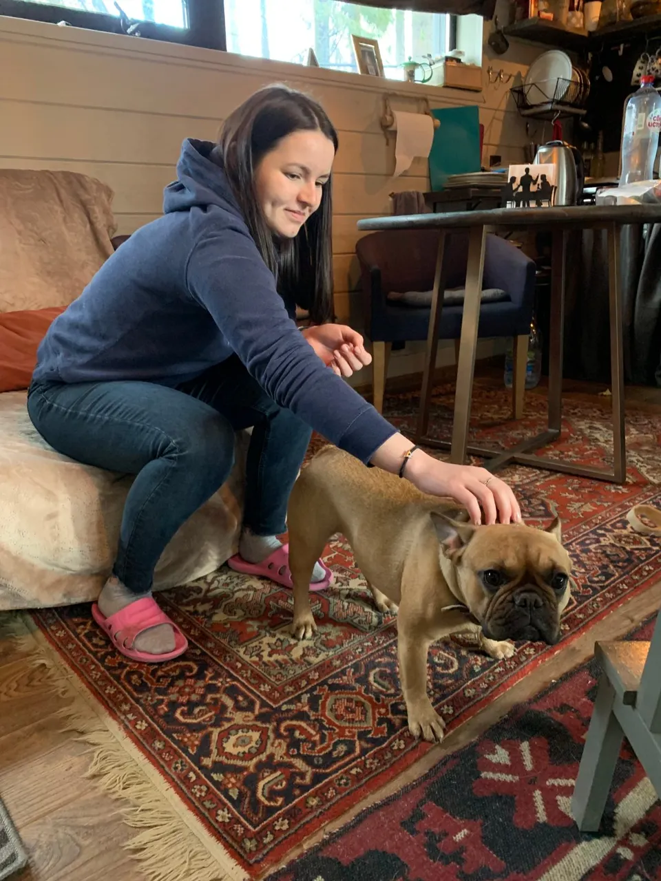 Anastasia acariciando a un perro pequeño de color marrón