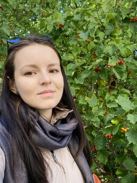 Anastasia al aire libre junto a hojas verdes